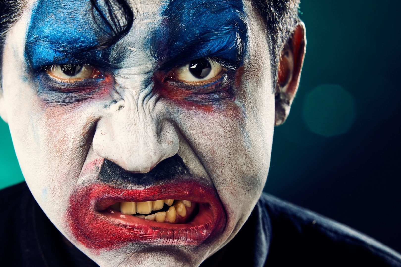 Ilustracja artykułu o porozumieniu bez przemocy. Na zdjęciu mężczyzna umalowany jak klaun, który robi minę, wykrywając usta.